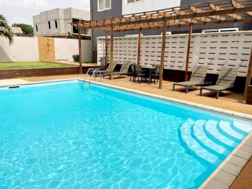 Una gran piscina azul con sillas y una mesa. en Regal Suites At Clifton Place en Accra
