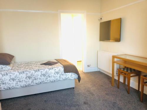 a bedroom with a bed and a desk and a television at AC Lounge 119 in Rochford