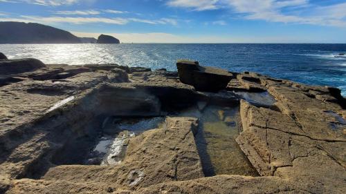 a group of rocks in the ocean with the water at Iruma INN in Minamiizu