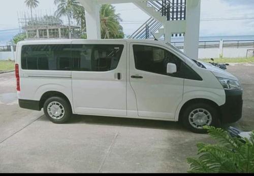 a white van parked in a parking lot at Elnora Delmar Travellers Inn in Siquijor