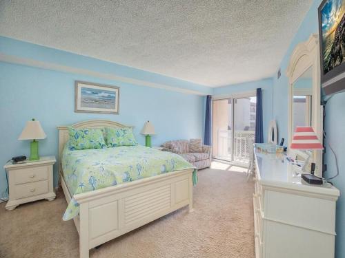 威爾伍德克拉斯特的住宿－1B/1B condo with Ocean views, Resort style, Free WIFI, Few steps to the Beach!!，一间拥有蓝色墙壁的卧室、一张床和窗户