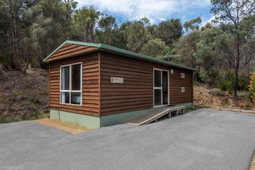 a small cabin with a bench in a parking lot at Hobart Bush Cabins in Kingston