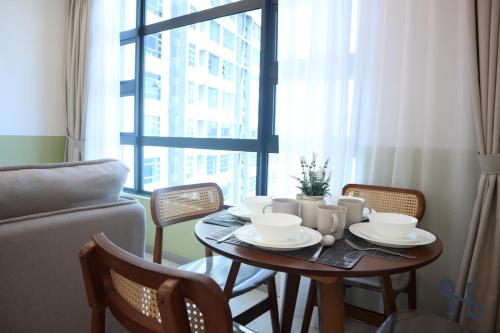a table with cups and plates on it in front of a window at Homesuite' Home at Jesselton Quay in Kota Kinabalu