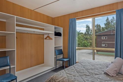 a bedroom with a bed and a large window at Hobart Bush Cabins in Kingston