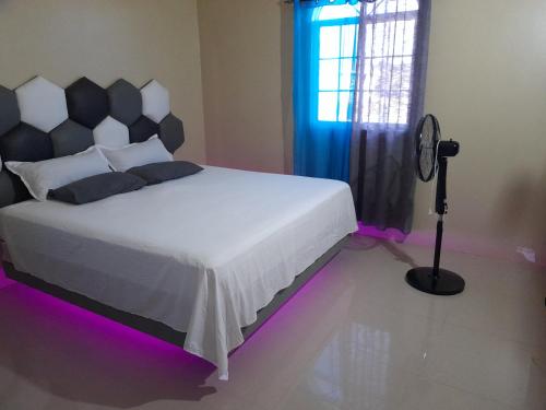 1 dormitorio con 1 cama blanca con luces moradas en Loodik Vacation Home Brompton Manor, en Black River