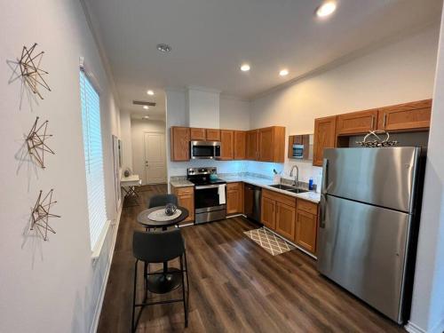 a kitchen with a stainless steel refrigerator and wooden cabinets at Urban chic living minutes to I-45 and I-610 #B in Houston