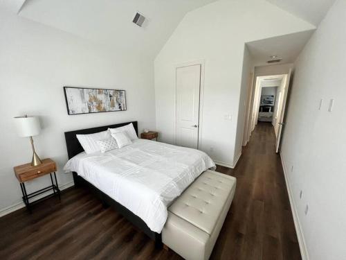 ein weißes Schlafzimmer mit einem Bett und einer Bank. in der Unterkunft Urban chic living minutes to I-45 and I-610 #B in Houston