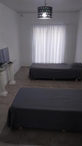 a bedroom with two beds and a white curtain at Adrogue Apart Airport Shuttle 24hs in Burzaco
