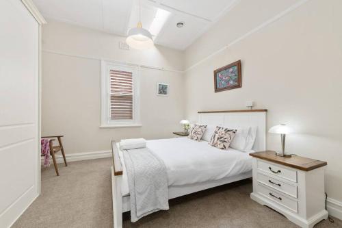 a white bedroom with a white bed and a table at Kyogle123 Central location in Orange