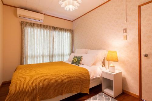 een slaapkamer met een bed met een gele deken en een raam bij condominium The First / Vacation STAY 81146 in Chatan