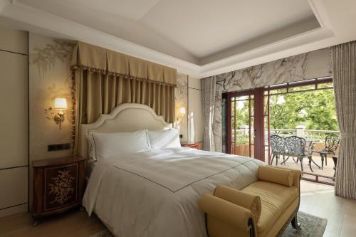 Hangzhou Qiushui Villa في هانغتشو: غرفة نوم بسرير وكرسي وشرفة