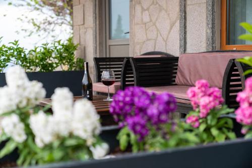 a wooden table with a glass of wine and flowers at Assos Kartal Yuvasi Hotel in Sazlı