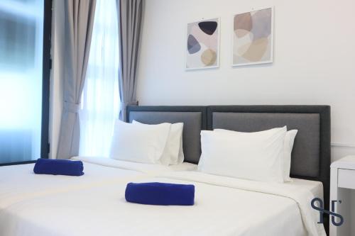two beds in a hotel room with white and blue pillows at Homesuite' Home at Jesselton Quay in Kota Kinabalu