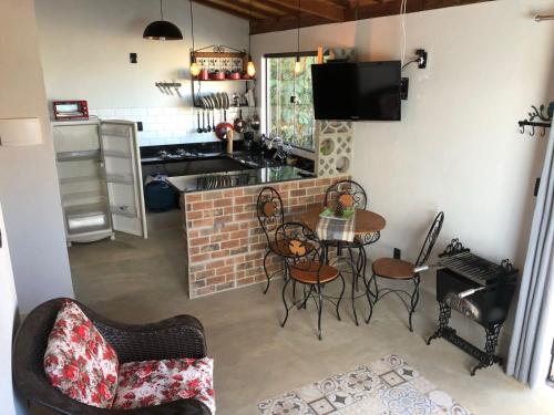 une cuisine avec une table et des chaises ainsi qu'une cheminée dans l'établissement Três Marias Chalés, à Conceição da Ibitipoca