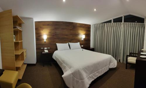 a hotel room with a large white bed and a chair at LA TERRAZA INN in Huancavelica