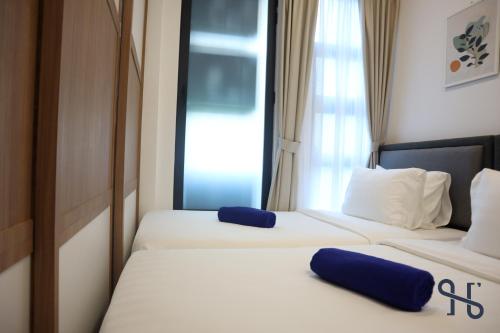 two beds in a hotel room with blue pillows at Homesuite' Home at Jesselton Quay in Kota Kinabalu