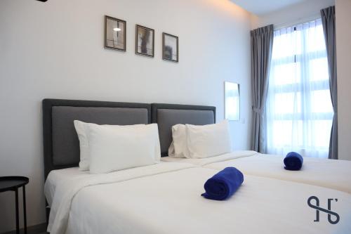 a bedroom with two beds with blue hats on them at Homesuite' Home at Jesselton Quay in Kota Kinabalu
