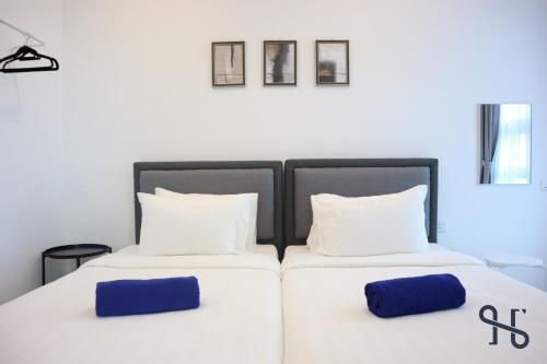 a bedroom with two beds with white and blue pillows at Homesuite' Home at Jesselton Quay in Kota Kinabalu