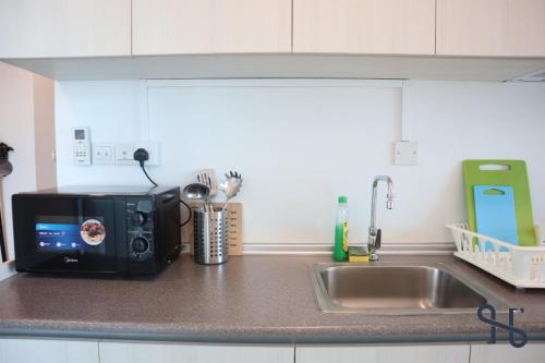 a microwave sitting on a kitchen counter next to a sink at Homesuite' Home at Jesselton Quay in Kota Kinabalu