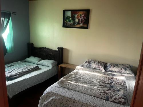 1 dormitorio con 2 camas y una foto en la pared en El Buda en Poás