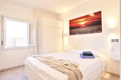a white bedroom with a bed with two books on it at Paradiso Pool Apartments by DomusAway in Costa Paradiso
