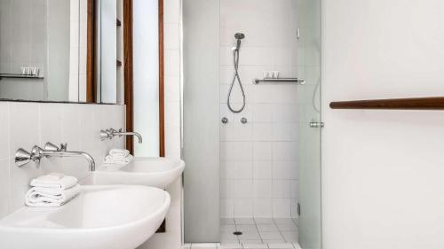 baño blanco con ducha y lavamanos en First Light, en Byron Bay