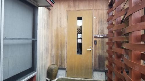 a hallway with a wooden door and a window at Shino's Farm Inn in Azumino