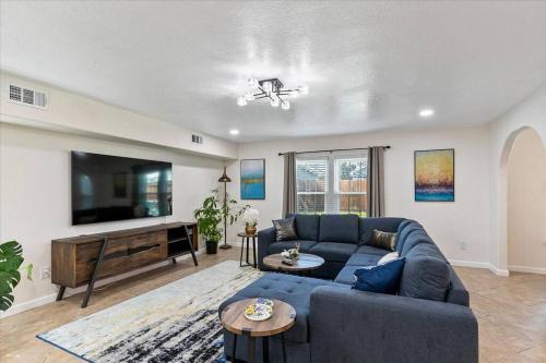 a living room with a blue couch and a flat screen tv at Bring the Crew! 4BR Luxe Pad, Backyard Magic & City at Your Door in Houston