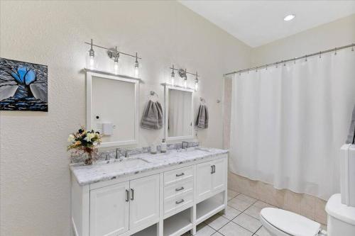 a white bathroom with a sink and a toilet at Bring the Crew! 4BR Luxe Pad, Backyard Magic & City at Your Door in Houston