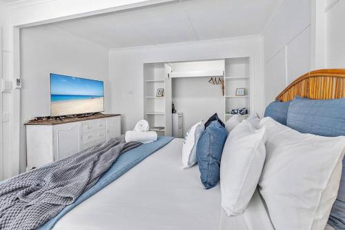 a white bedroom with a large bed and a television at Luxury Coastal Retreat in Coolum Beach