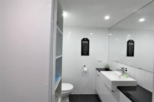 a white bathroom with a sink and a toilet at CBD apartment Cairns waterfront in Cairns