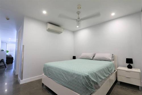 a white bedroom with a bed and a white wall at CBD apartment Cairns waterfront in Cairns