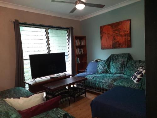 a living room with a couch and a flat screen tv at Daintree Rainforest Accommodation in Cow Bay
