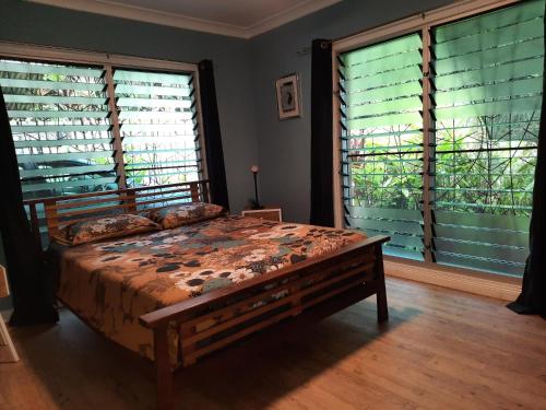 Daintree Rainforest Accommodation في Cow Bay: غرفة نوم بسرير كبير في غرفة بها نوافذ