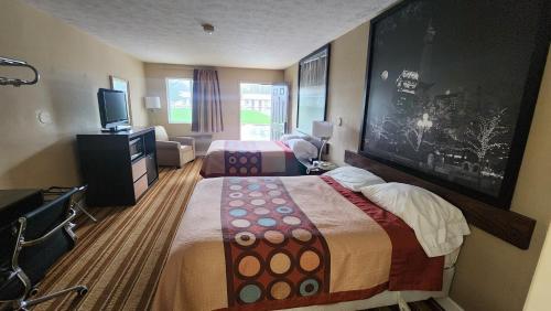 a hotel room with two beds and a flat screen tv at Super 8 by Wyndham Centerville-Richmond in Centerville