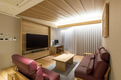 a living room with a couch and a television at Kinzan in Kobe