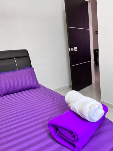 uma cama com lençóis roxos e toalhas em RAINA MUSLIM FRIENDLY HOMESTAY Perlis em Arau