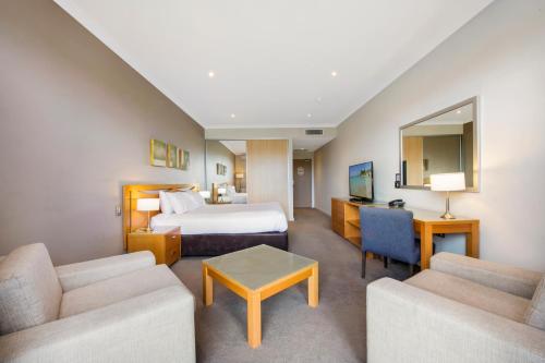 a hotel room with a bed and two couches at Mercure Kooindah Waters Central Coast in Wyong