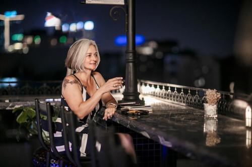 a woman sitting at a table with a glass of wine at JM Marvel Hotel & Spa in Hanoi
