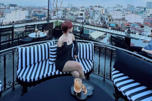 a woman sitting on a bench on a balcony at JM Marvel Hotel & Spa in Hanoi