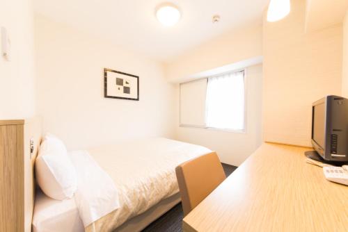 sypialnia z łóżkiem i biurkiem z telewizorem w obiekcie Hotel il Grande Umeda w Osace