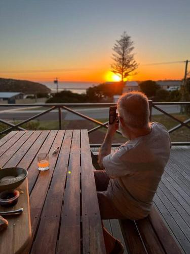 a man sitting on a picnic table taking a picture of the sunset at Moore to Sea~Spectacular views in stylish comfort in Guilderton