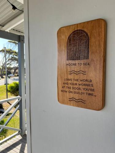 a wooden sign on a wall with a window at Moore to Sea~Spectacular views in stylish comfort in Guilderton