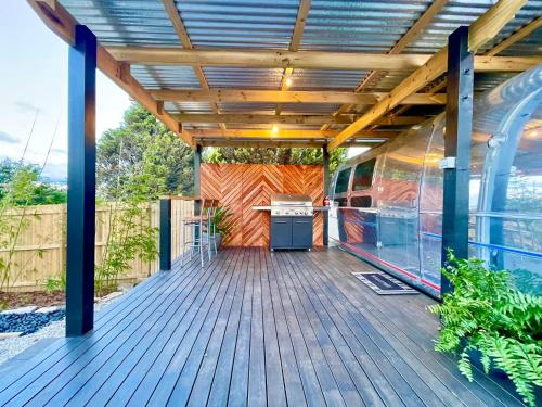 an outdoor deck with a grill and a building at Frankie the Silver Bullet Airstream in Katoomba