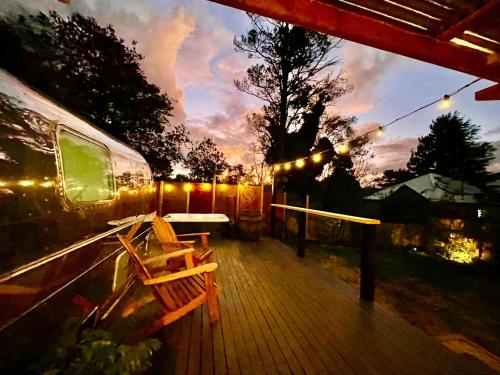 eine Terrasse mit einer Bank, einem Tisch und einem Zug in der Unterkunft Frankie the Silver Bullet Airstream in Katoomba