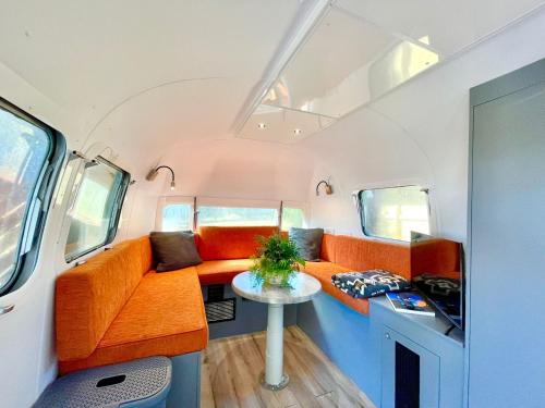 salon z pomarańczowymi kanapami i stołem w obiekcie Frankie the Silver Bullet Airstream w mieście Katoomba
