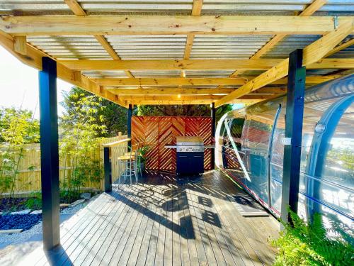 a wooden deck with a wooden roof with a table at Frankie the Silver Bullet Airstream in Katoomba