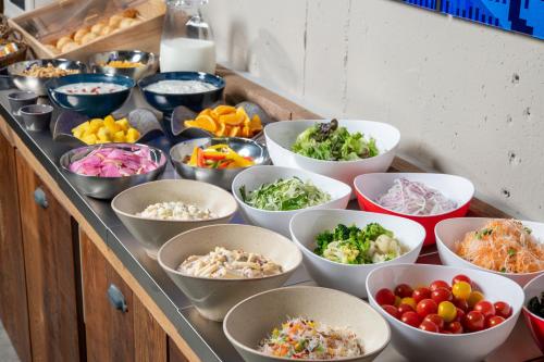 a buffet filled with bowls of different types of food at HOTEL MYSTAYS Okayama in Okayama
