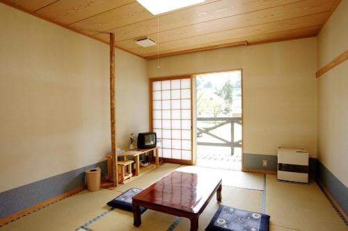 sala de estar con mesa y ventana grande en Katakuri no Yado, en Tsunan