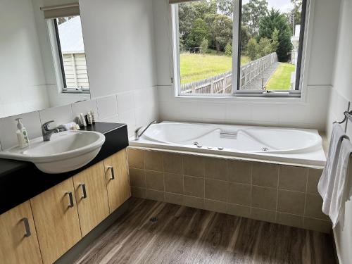 a bathroom with a tub and a sink and a window at McMillans of Metung Coastal Resort in Metung